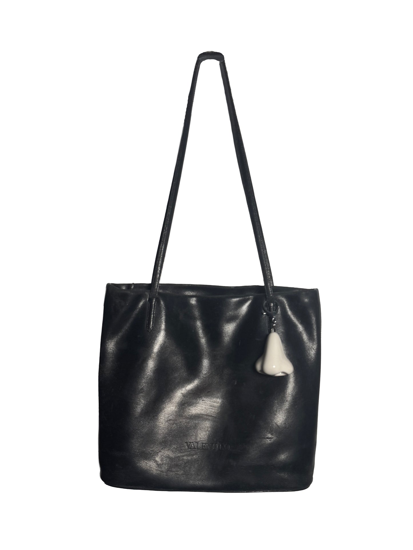 Black leather tote bag with a white nose keychain on a white background