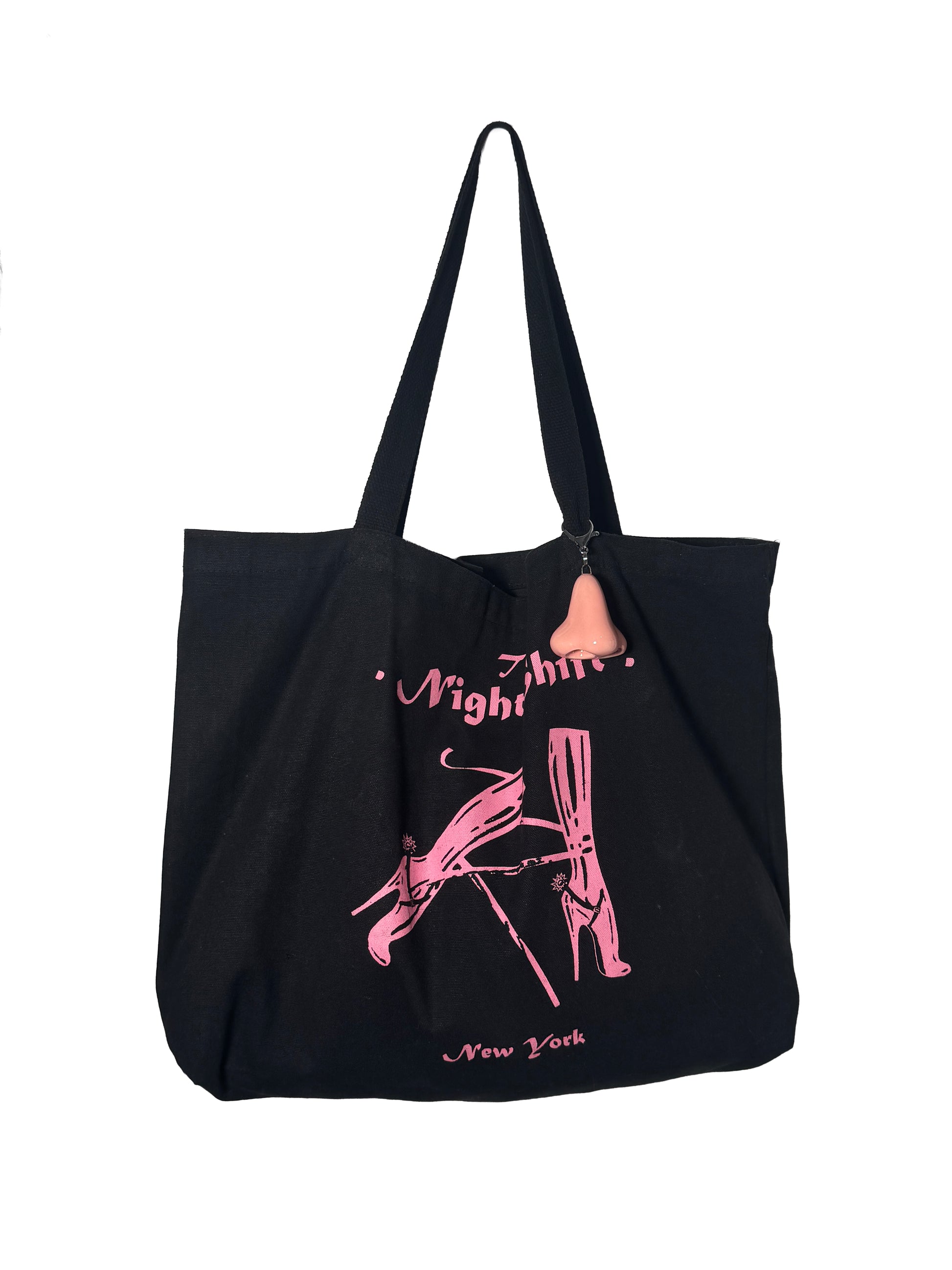 Black tote bag with pink graphics and text and a pink nose shaped keychain on a white background
